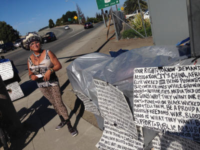 Redwood City sues to get woman and her signs off street corner
